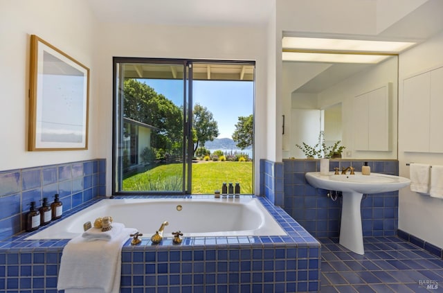 bathroom featuring a wealth of natural light, tile patterned flooring, a garden tub, and a sink