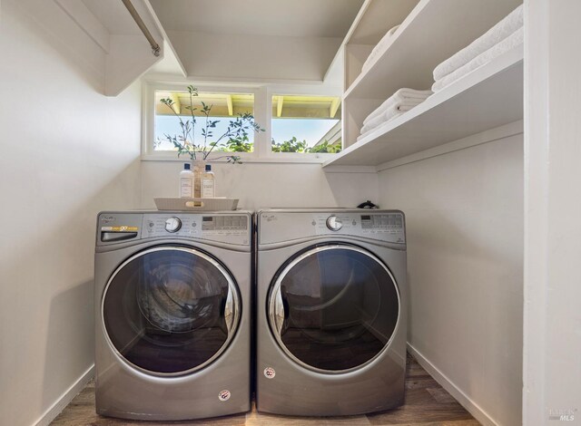 laundry area with washing machine and clothes dryer, baseboards, laundry area, and wood finished floors