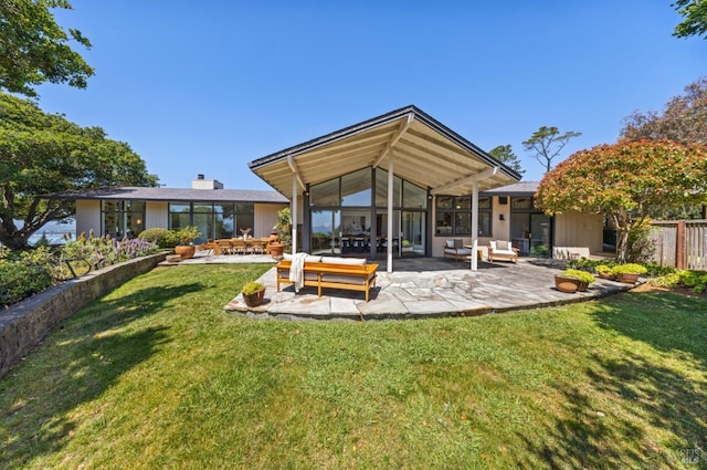 back of property with an outdoor hangout area, a patio area, and a lawn