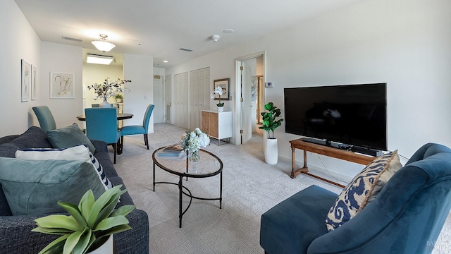 living room featuring light colored carpet, baseboards, and visible vents
