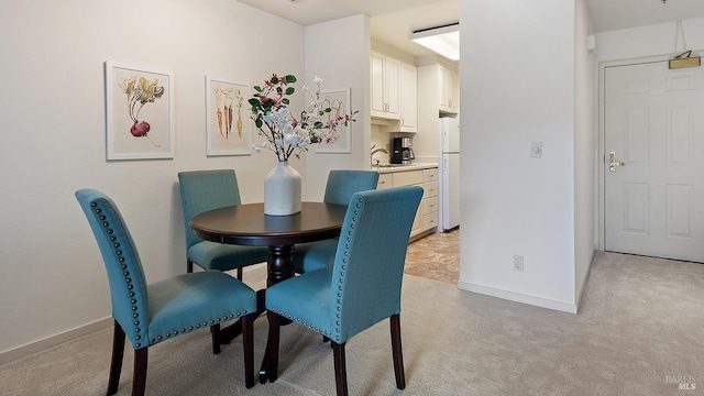 dining area featuring baseboards and light carpet