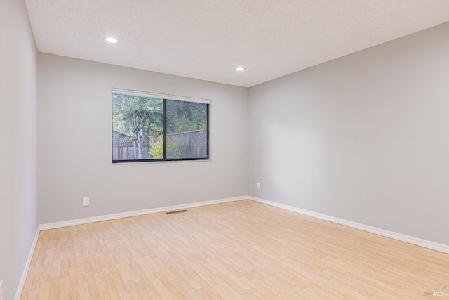 empty room with light wood-style floors, baseboards, recessed lighting, and visible vents
