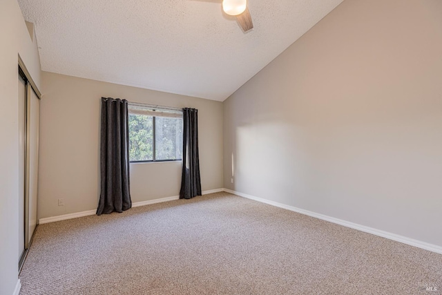 carpeted spare room with baseboards, a ceiling fan, a textured ceiling, and lofted ceiling