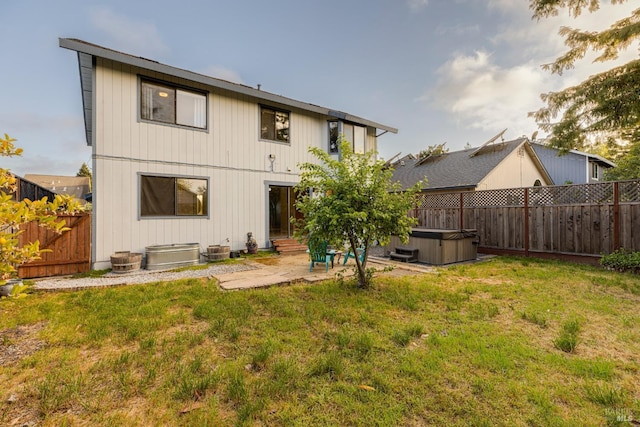 back of house with a hot tub, a yard, a fenced backyard, and a patio area
