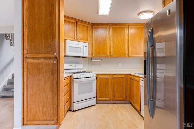 kitchen featuring white appliances, brown cabinetry, light wood finished floors, and light countertops