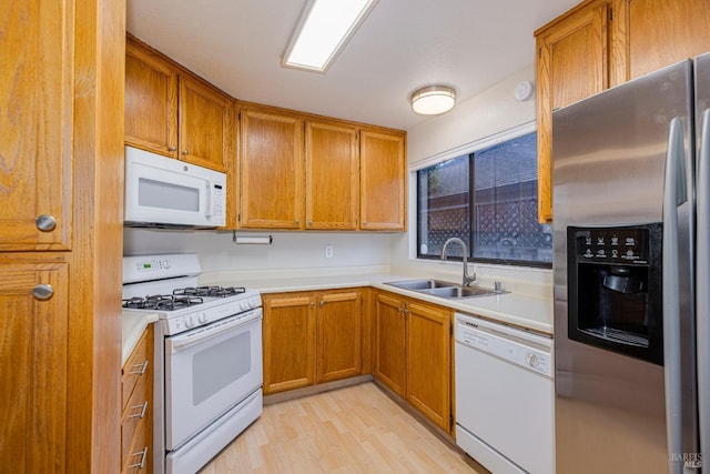 kitchen with a sink, light countertops, brown cabinetry, and white appliances