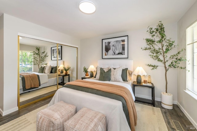 bedroom featuring baseboards, visible vents, wood finished floors, and a closet