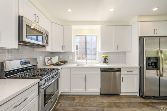 kitchen featuring white cabinets, a sink, light countertops, stainless steel appliances, and decorative backsplash