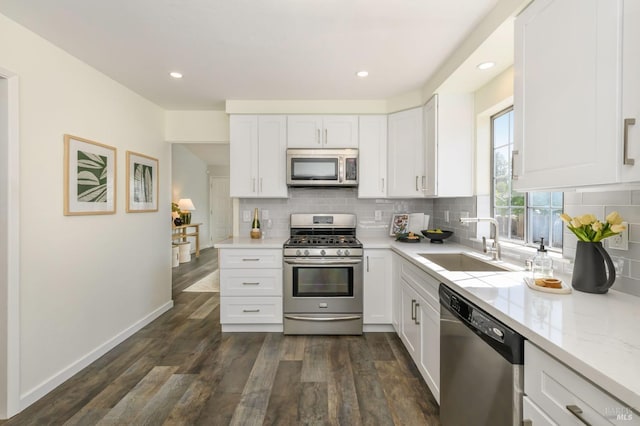 kitchen featuring a sink, appliances with stainless steel finishes, decorative backsplash, and white cabinets