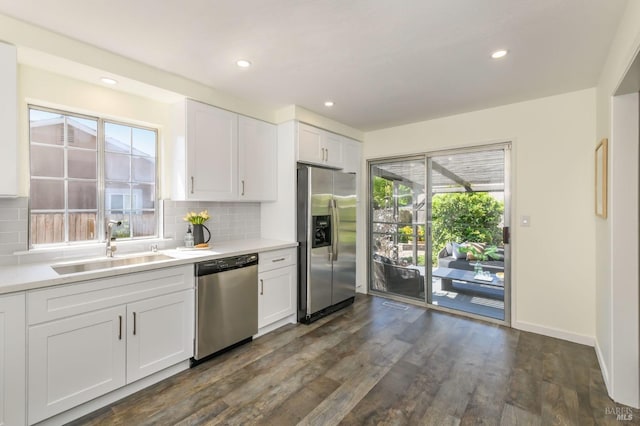 kitchen featuring a sink, appliances with stainless steel finishes, decorative backsplash, and dark wood-style floors