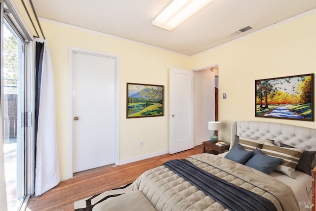 bedroom featuring visible vents, ornamental molding, baseboards, and wood finished floors