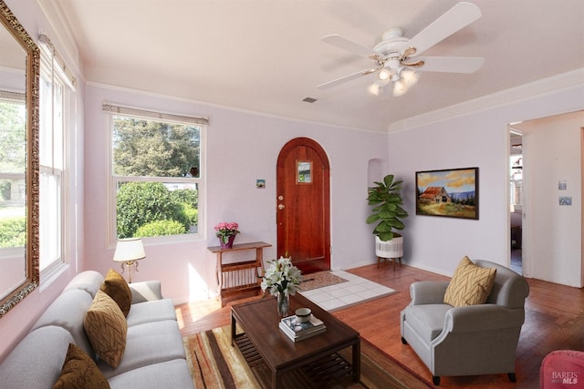 living area featuring a healthy amount of sunlight, arched walkways, a ceiling fan, and wood finished floors