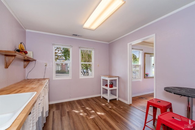 interior space with visible vents, a sink, baseboards, dark wood-style floors, and ornamental molding