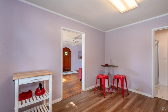 interior space with crown molding, arched walkways, baseboards, and wood finished floors