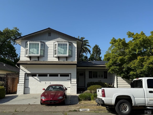view of front of home with fence, driveway, and a garage