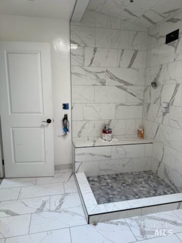 bathroom featuring marble finish floor and a tile shower