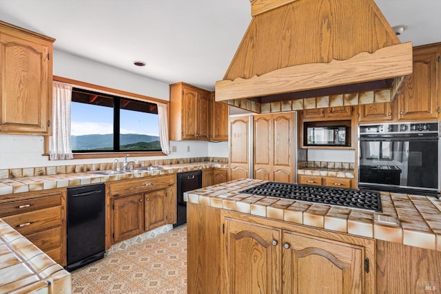 kitchen featuring a sink, tile counters, black appliances, and premium range hood