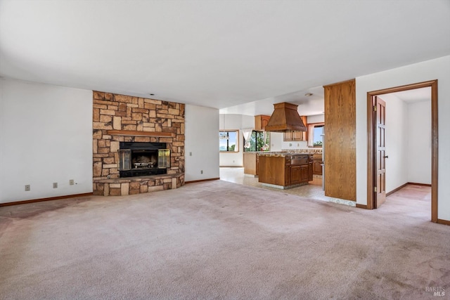 unfurnished living room featuring a fireplace, light colored carpet, and baseboards