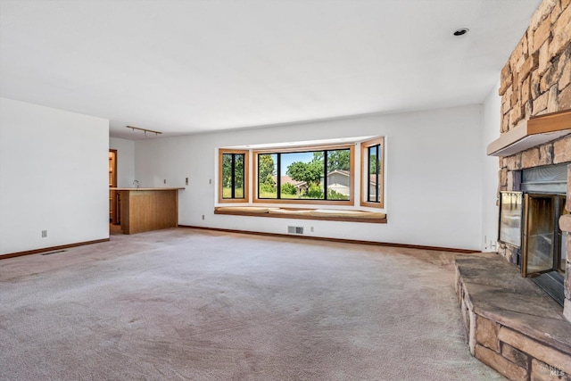 unfurnished living room featuring light colored carpet, visible vents, a fireplace, and baseboards