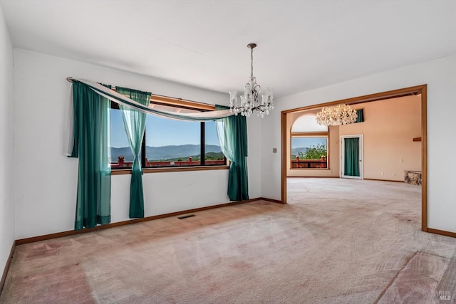 carpeted empty room with baseboards, a chandelier, and visible vents