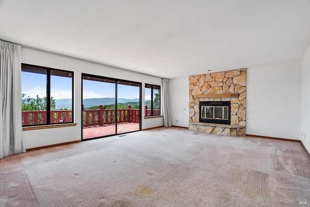 unfurnished living room featuring a mountain view, carpet, baseboards, and a fireplace
