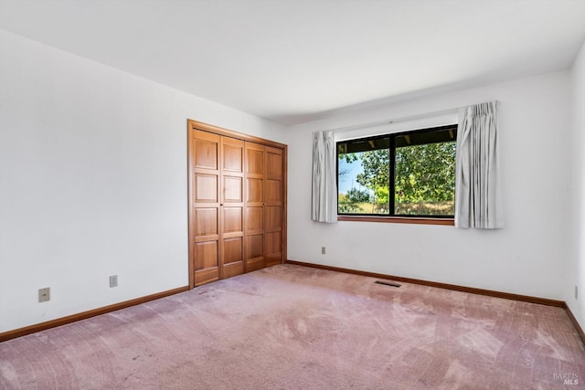 unfurnished bedroom with baseboards, carpet flooring, a closet, and visible vents