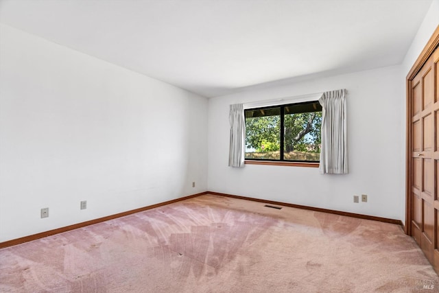 unfurnished room featuring baseboards, light carpet, and visible vents