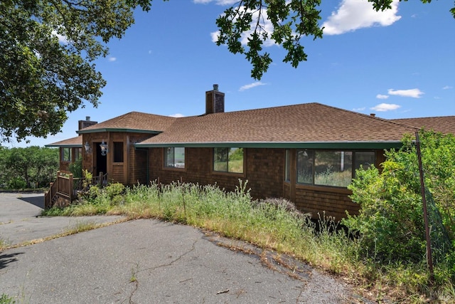 single story home featuring a shingled roof and a chimney