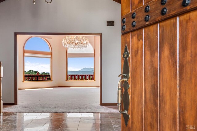 interior space with baseboards, an inviting chandelier, and a towering ceiling