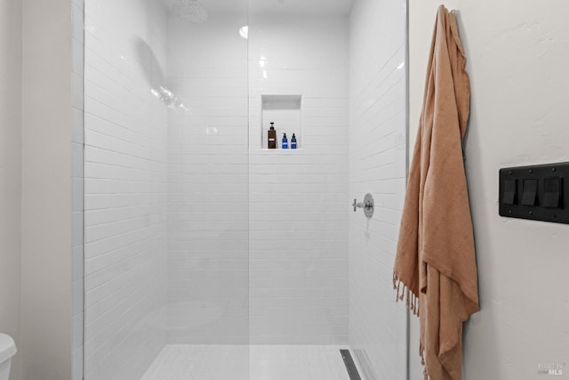 full bathroom featuring toilet and tiled shower