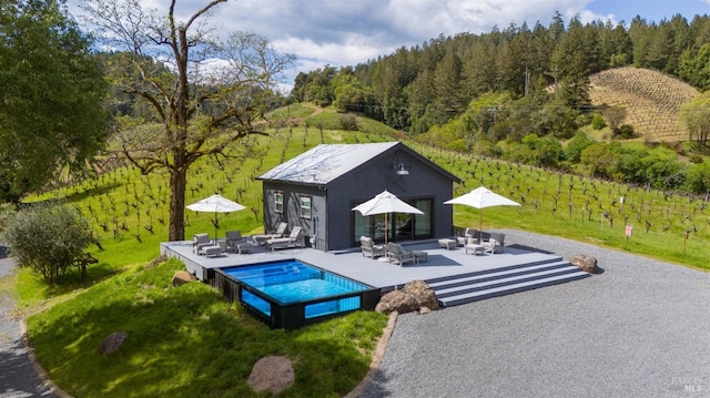 pool with a view of trees, an outdoor living space, outdoor dining space, and a patio area