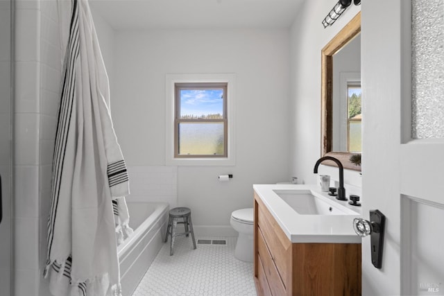 bathroom featuring toilet, plenty of natural light, a tub to relax in, and vanity