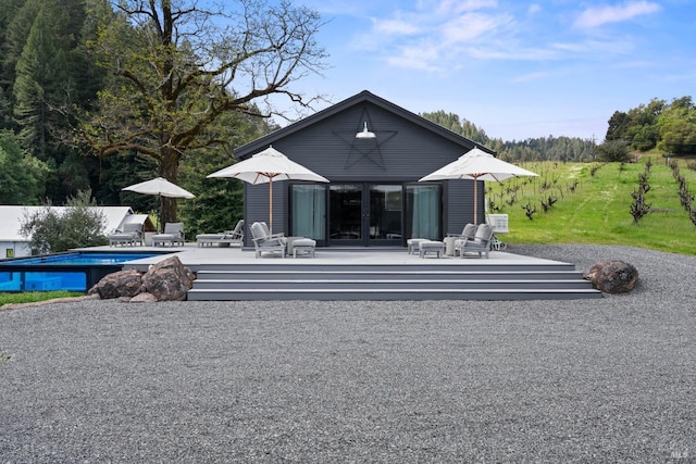 rear view of property with an exterior structure, a deck, a fenced in pool, and an outdoor structure