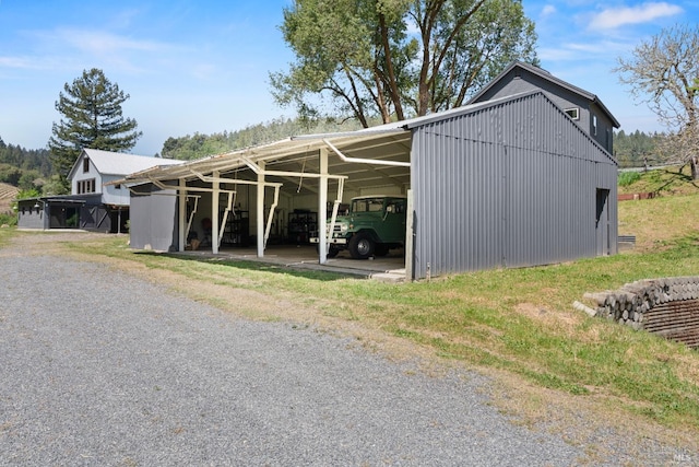 view of car parking with gravel driveway, an outbuilding, and a carport