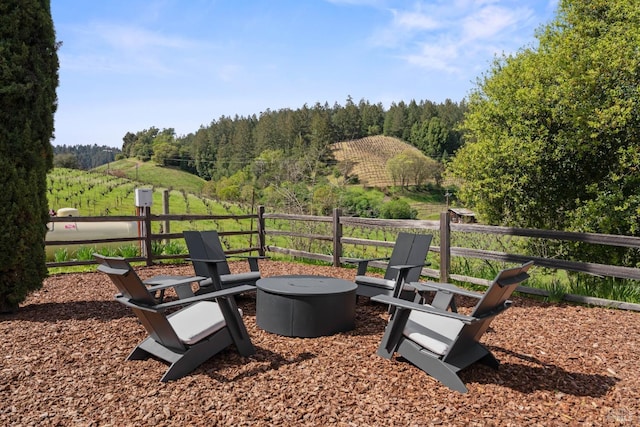 view of patio / terrace with a wooded view, a fire pit, and a rural view