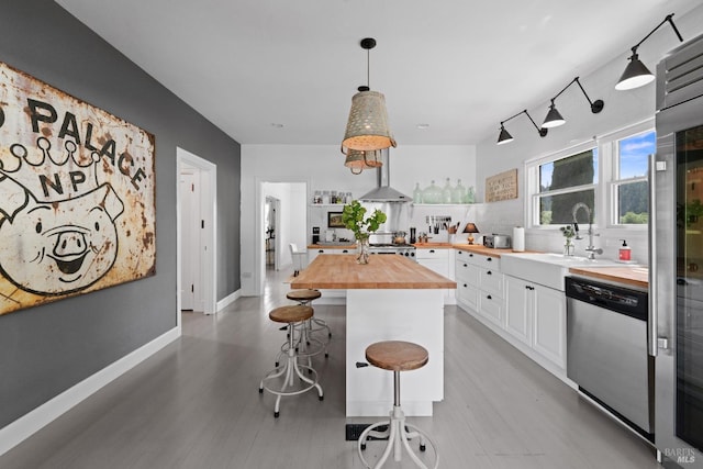 kitchen featuring decorative backsplash, a kitchen breakfast bar, dishwasher, a sink, and butcher block counters