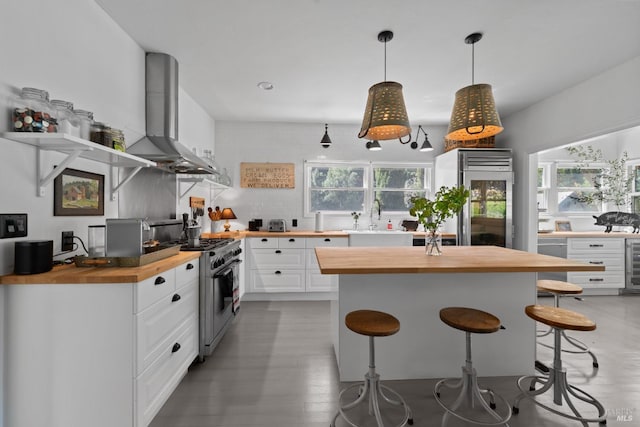 kitchen featuring open shelves, butcher block countertops, wall chimney exhaust hood, tasteful backsplash, and appliances with stainless steel finishes