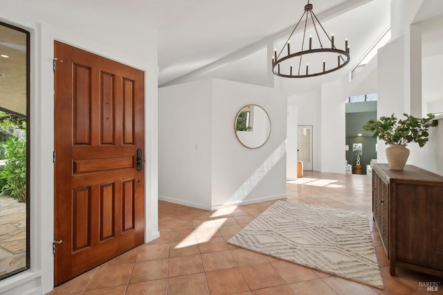 tiled foyer entrance with baseboards, high vaulted ceiling, and a chandelier