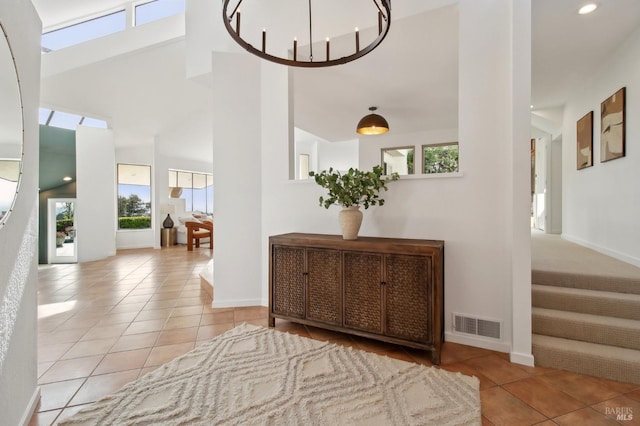 hallway with visible vents, baseboards, tile patterned floors, and a wealth of natural light
