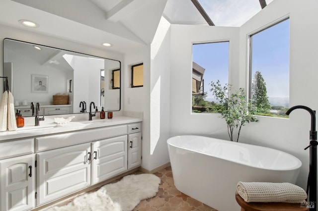 bathroom with lofted ceiling with beams, vanity, recessed lighting, baseboards, and a soaking tub