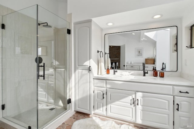 bathroom featuring double vanity, a sink, a stall shower, and recessed lighting