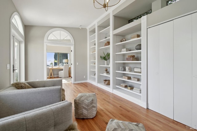 living area with a chandelier, built in features, a wealth of natural light, and light wood-type flooring