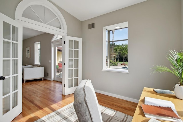 office space featuring baseboards, visible vents, french doors, and light wood finished floors