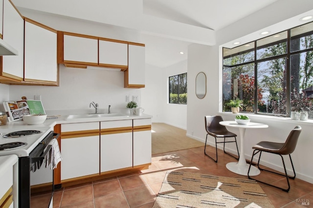 kitchen featuring a sink, electric range oven, light countertops, white cabinetry, and light tile patterned floors