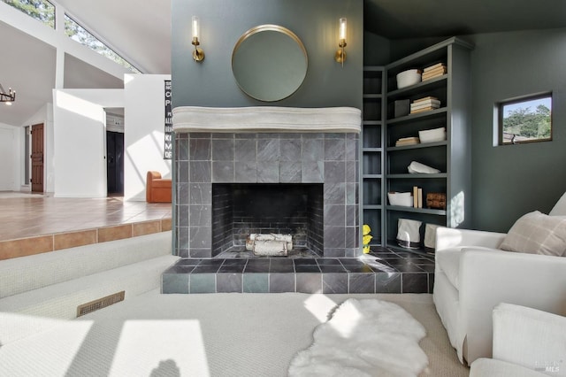 living room with a healthy amount of sunlight, built in features, a fireplace, and vaulted ceiling
