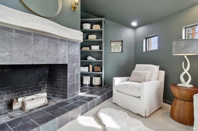 living area with carpet floors, vaulted ceiling, and a fireplace