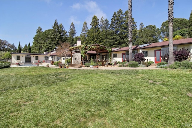exterior space with a yard, a patio, a chimney, and roof mounted solar panels