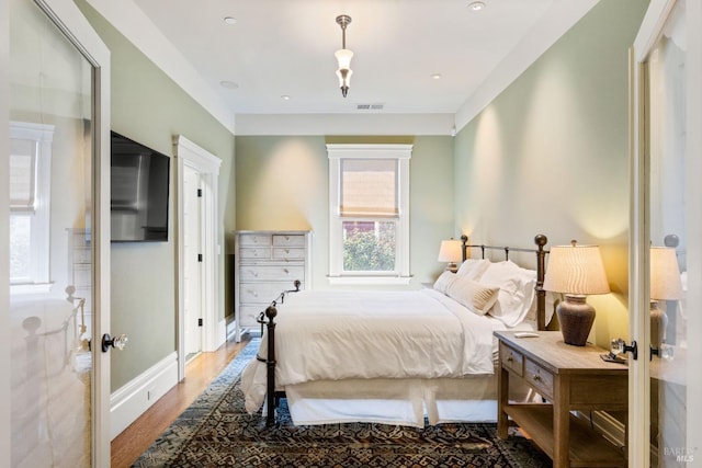 bedroom with visible vents, baseboards, and wood finished floors
