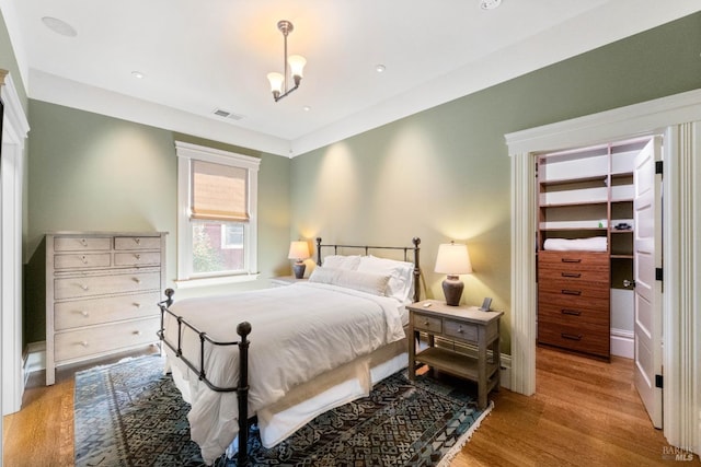 bedroom featuring a walk in closet, wood finished floors, and visible vents