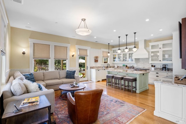 living room featuring recessed lighting, a wainscoted wall, light wood-type flooring, and visible vents